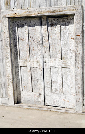 Porte in legno intemperie che pende sul marciapiede con iniziali intagliate su tutta la superficie, Locke, California Delta, California, USA Foto Stock