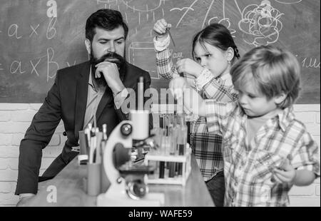 Microscopio strumento ottico a scienza classe. torna a scuola. bambini felici insegnante. Imparare mediante microscopio a scuola lezione. Inizio dello sviluppo dei bambini. Cordiali figli in laboratorio Foto Stock