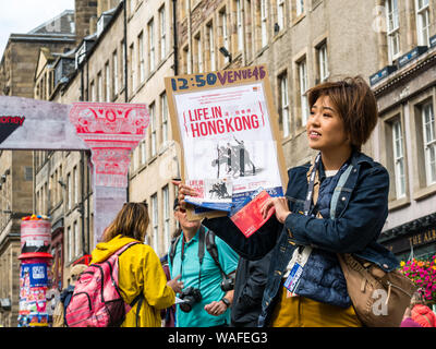 Edimburgo, Scozia, Regno Unito, 20 agosto 2019. Edinburgh Festival Fringe: esecutori sul Royal Mile tentare di attirare le persone per i loro spettacoli. Artisti provenienti da uno spettacolo chiamato Vita in Hong Kong, un mime sulla vita quotidiana e scene di Hong Kong Foto Stock