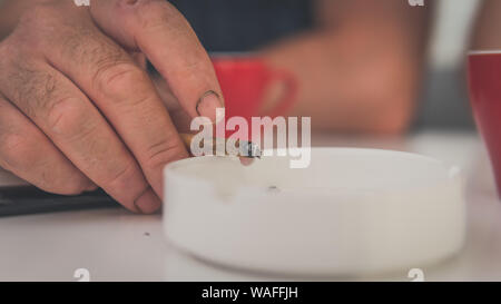 La marijuana medica in comune la mano, close-up. Fumare cannabis blunt in ambienti chiusi. La canapa è un concetto di medicina a base di erbe Foto Stock