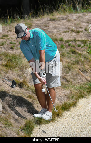 Il Golfer colpendo un duro colpo al di fuori del ruvido dietro una trappola di sabbia Foto Stock