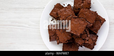 Home-cotta brownie al cioccolato su una piastra bianca su una bianca superficie di legno. Piatto, laici overhead, dall'alto. Spazio per il testo. Foto Stock