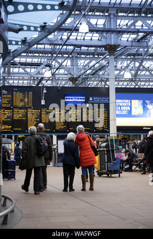 Le persone in piedi che guarda a partenze e arrivi passeggeri schede di informazione nella stazione ferroviaria Waverley di Edimburgo in Scozia UK Foto Stock