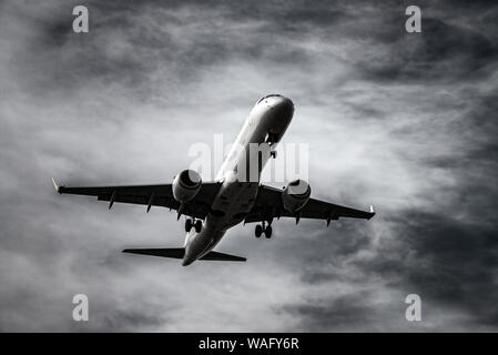 Atterraggio aereo nella parte anteriore del cielo drammatico in bianco e nero Foto Stock