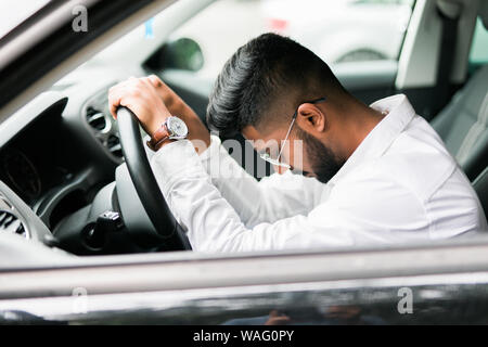 Closeup ritratto stanco giovane uomo bello con breve durata dell'attenzione, alla guida della sua auto dopo lunghe ore di viaggio, cercando di rimanere sveglio a ruota, unità organizzativa isolato Foto Stock