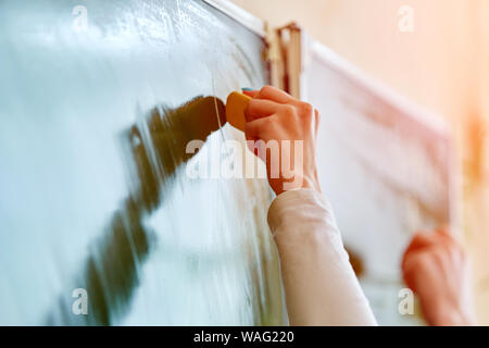 Soft focus Lavagna blu o verde bordo. Studente di scuola superiore della mano che tiene bianco gesso la scrittura sulla scheda verde in aula .concetto di istruzione. Foto Stock