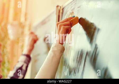 Soft focus Lavagna blu o verde bordo. Studente di scuola superiore della mano che tiene bianco gesso la scrittura sulla scheda verde in aula .concetto di istruzione. Foto Stock