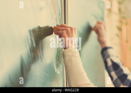 Soft focus Lavagna blu o verde bordo. Studente di scuola superiore della mano che tiene bianco gesso la scrittura sulla scheda verde in aula .concetto di istruzione. Foto Stock