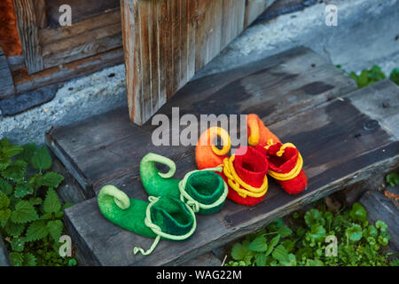 Due coppie di nani scarpe di feltro all'ingresso di una vecchia casa in legno. I nani è venuto a visitare. Foto Stock