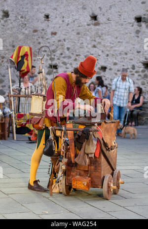 FILETTO, Italia - 11 agosto 2019: un buffone mago cerca per qualche elemento nella sua casella di trucchi. Villaggio annuale festival in un autentico borgo medievale Foto Stock