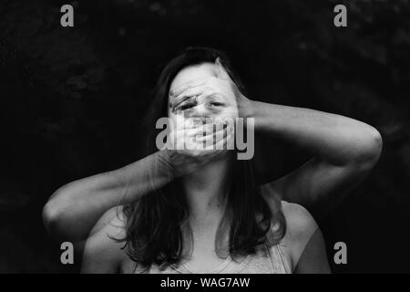 In bianco e nero con doppia esposizione ritratto di donna dietro le mani Foto Stock