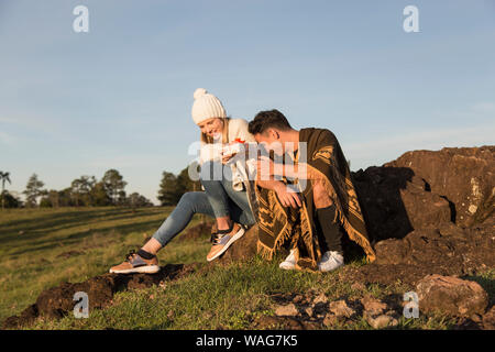 Ispanico uomo e donna caucasica scambio di doni sulle rocce un pomeriggio autunnale con un sacco di sole Foto Stock