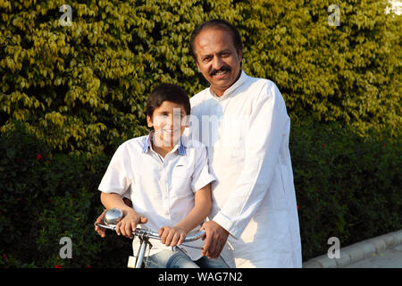 Indian vecchio uomo equitazione Bicicletta con il nipote Foto Stock