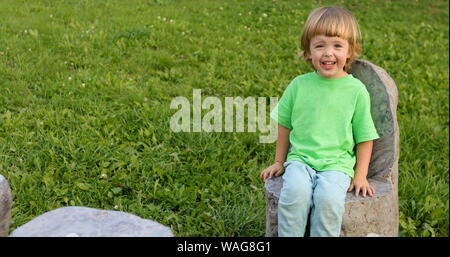 Bambino seduto sulla sedia di pietra in posizione di parcheggio Foto Stock