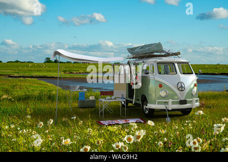 Road Trip, un classico VW camper parcheggiato dietro un mare di Wadden dike nella Germania del nord Foto Stock