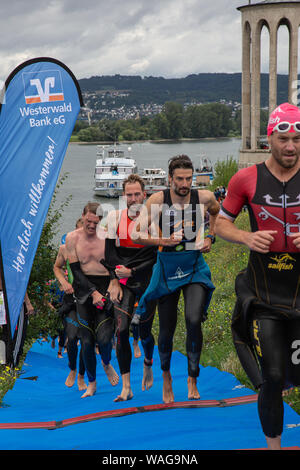 Neuwied, Renania Palatinato, Germania - 18 agosto 2019: i concorrenti della società Raiffeisen triathlon dopo una nuotata in esecuzione per la loro corsa biciclette Foto Stock