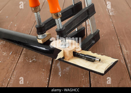 La riparazione di una chitarra e il servizio di assistenza - Closeup il serraggio di una chitarra collo sfondo di legno Foto Stock