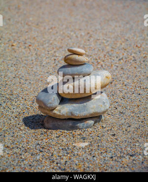 Primo piano di pietre impilate sulla spiaggia. Sette pietre bilanciate l'una sull'altra su una spiaggia di sabbia a Creta. Foto Stock