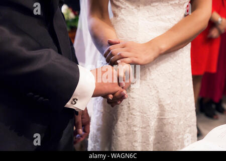 Tenere la mani durante la cerimonia di nozze Foto Stock