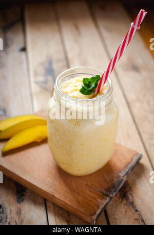 Frullato di mango in un recipiente su un tavolo di legno Foto Stock