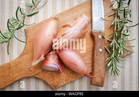 Close-up di scalogno con rosmarino fresco sul tagliere, vista dall'alto Foto Stock