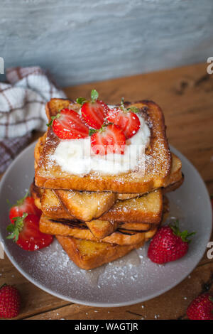 Toast alla francese con fragole fresche, filamenti di cocco e miele, su sfondo di legno Foto Stock