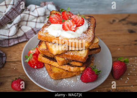 Toast alla francese con fragole fresche, filamenti di cocco e miele, su sfondo di legno Foto Stock