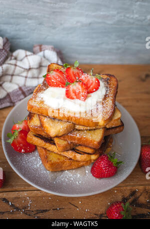 Toast alla francese con fragole fresche, filamenti di cocco e miele, su sfondo di legno Foto Stock