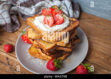 Toast alla francese con fragole fresche, filamenti di cocco e miele, su sfondo di legno Foto Stock