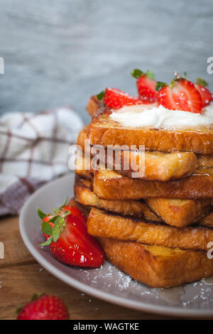 Close-up di toast alla francese con fragole fresche, filamenti di cocco e miele, su sfondo di legno Foto Stock