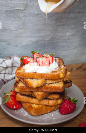 Toast alla francese con fragole fresche, filamenti di cocco e gocce di miele, su sfondo di legno Foto Stock