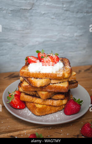 Toast alla francese con fragole fresche, filamenti di cocco e miele, su sfondo di legno Foto Stock