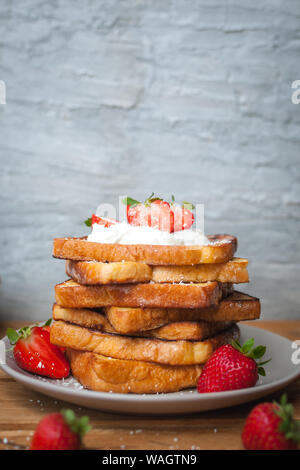 Toast alla francese con fragole fresche, filamenti di cocco e miele, su sfondo di legno Foto Stock