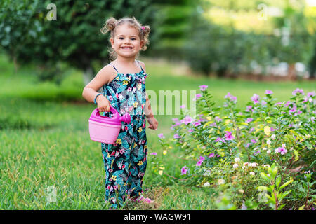 Carino bambina fiori di irrigazione nel giardino in estate Foto Stock