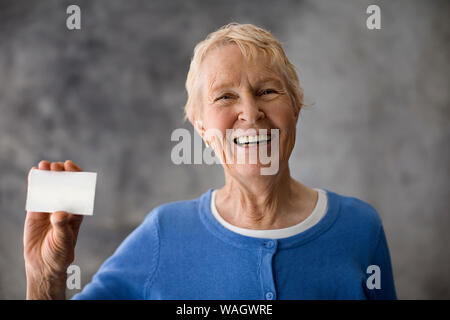 Senior donna con in mano una carta bianca. Foto Stock