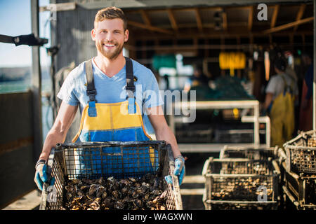 Giovane uomo mostra catturati i molluschi e i crostacei. Foto Stock