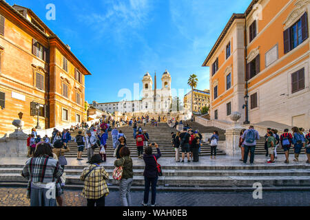 I turisti affollano la Piazza di Spagna con la scalinata di Piazza di Spagna e Trinità dei Monti chiesa in background in una giornata di sole in Roma, Italia Foto Stock