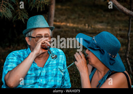Felice senior amare giovane di bere vino e avente un grande momento insieme su un picnic nel parco Foto Stock