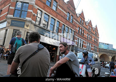 Amici di sesso maschile parlando seduti fuori in strada vicino Monmouth Cheese Company dal Mercato di Borough entrata nel sud di Londra Inghilterra REGNO UNITO KATHY DEWITT Foto Stock