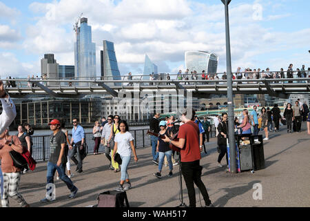 I turisti a piedi lungo street & busker musicista di strada al di fuori della galleria d'arte Tate Modern Bankside con vista della città di Londra Inghilterra KATHY DEWITT Foto Stock