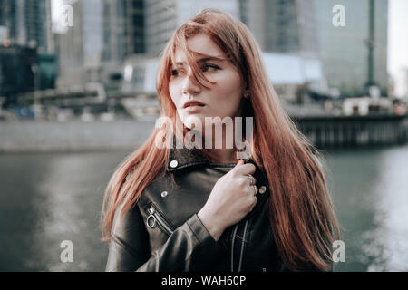 Taglie donna con i capelli rossi che indossa vestito blu e cuoio giacca nera Foto Stock