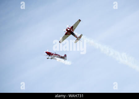 Un Extra 300 Duo display all'Airshow di fumo inclyding sentieri, formazione, synchronoized dive con radio controllato la versione in miniatura Foto Stock