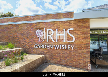 Logo e nome segno su un muro di mattoni al nuovo ingresso alla RHS Garden, Wisley, Surrey, una popolare attrazione turistica nel sud-est Inghilterra Foto Stock