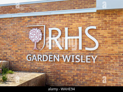 Logo e nome segno su un muro di mattoni al nuovo ingresso alla RHS Garden, Wisley, Surrey, una popolare attrazione turistica nel sud-est Inghilterra Foto Stock