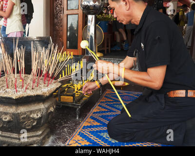 BANGKOK, Tailandia- giugno, 21, 2017: tailandese uomo accendere una candela al Wat Pho tempio a Bangkok Foto Stock