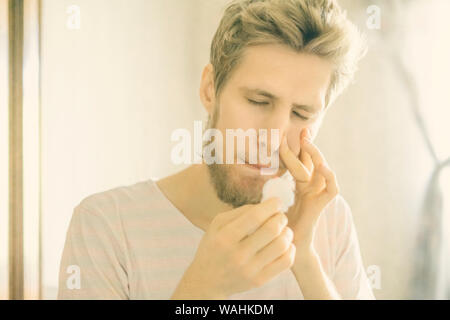 primo piano ritratto uomo con bearded soffrire di sanguinamento dal naso usando tampone d'ovatta f Foto Stock