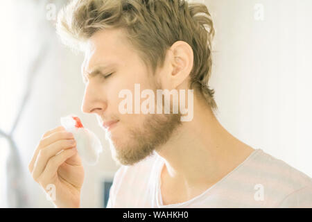 primo piano ritratto uomo con bearded soffrire di sanguinamento dal naso usando tampone d'ovatta f Foto Stock