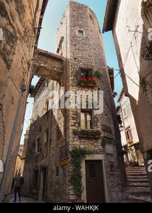 Una pietra di strette strade lastricate e vecchie case medievali con arcate di porte in legno anche metallo tende alle finestre in cittadina antica Sermoneta, Italia Foto Stock