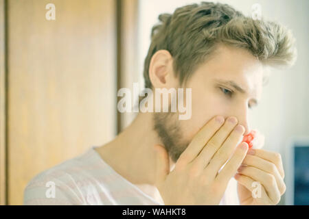 primo piano ritratto uomo con bearded soffrire di sanguinamento dal naso usando tampone d'ovatta f Foto Stock