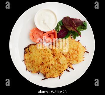 Frittelle di patate con filetto di salmone e salsa cremosa isolati su sfondo nero Foto Stock